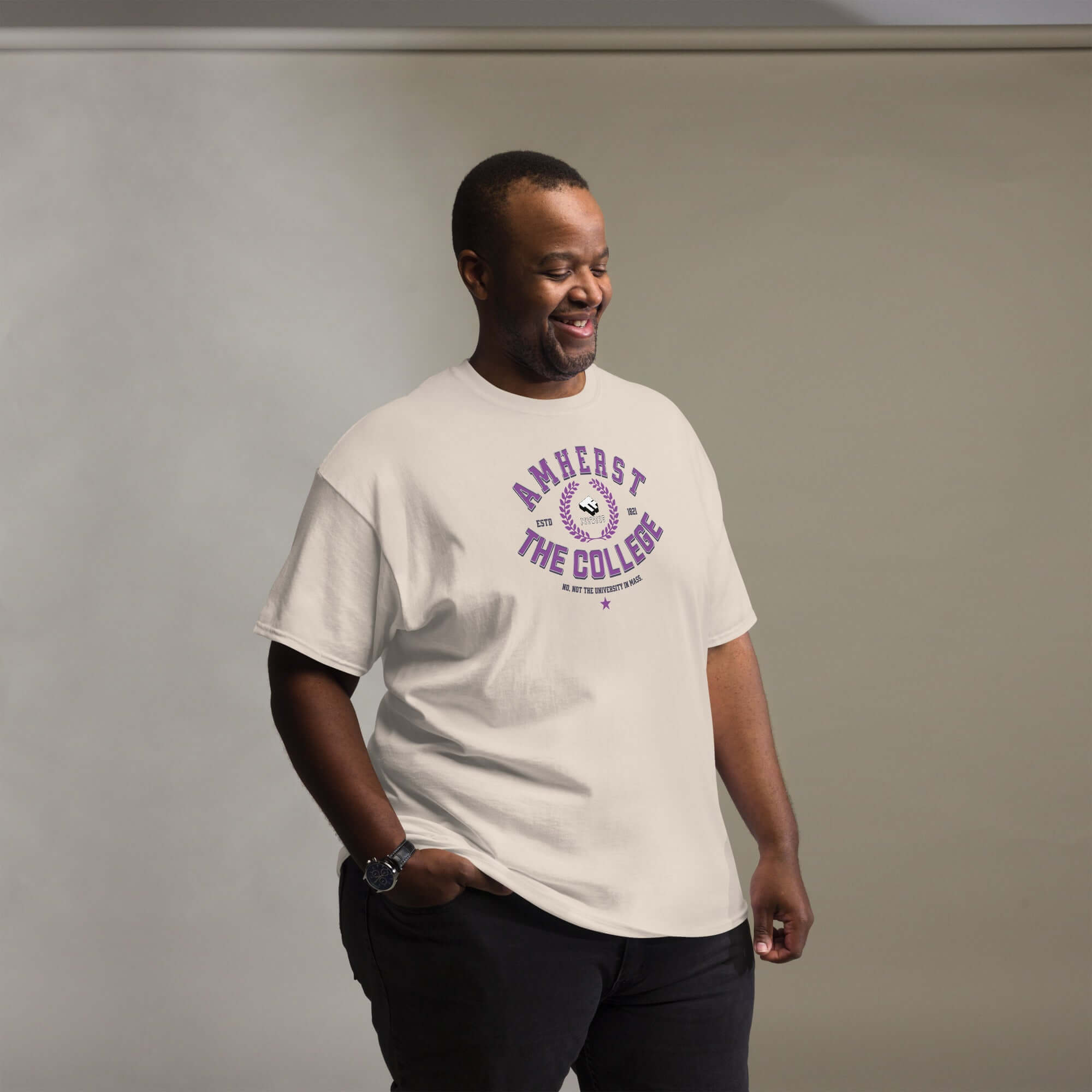 Man wearing cream Amherst Clarification T-Shirt with purple text 'THE COLLEGE,' combining style with humor and identity.
