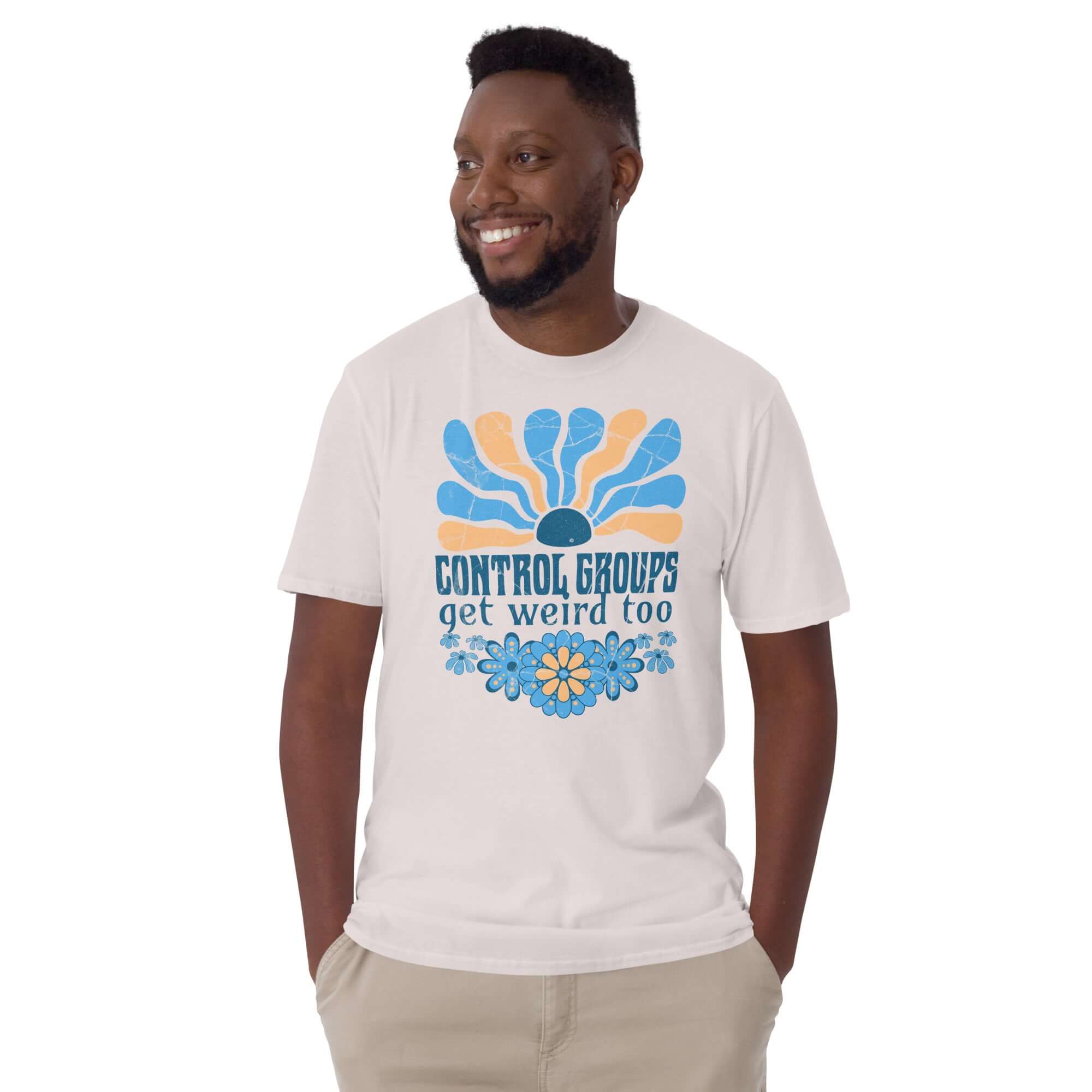 Man wearing a 'Control Groups Get Weird Too' t-shirt with retro blue and orange sunburst design, showcasing science humor.