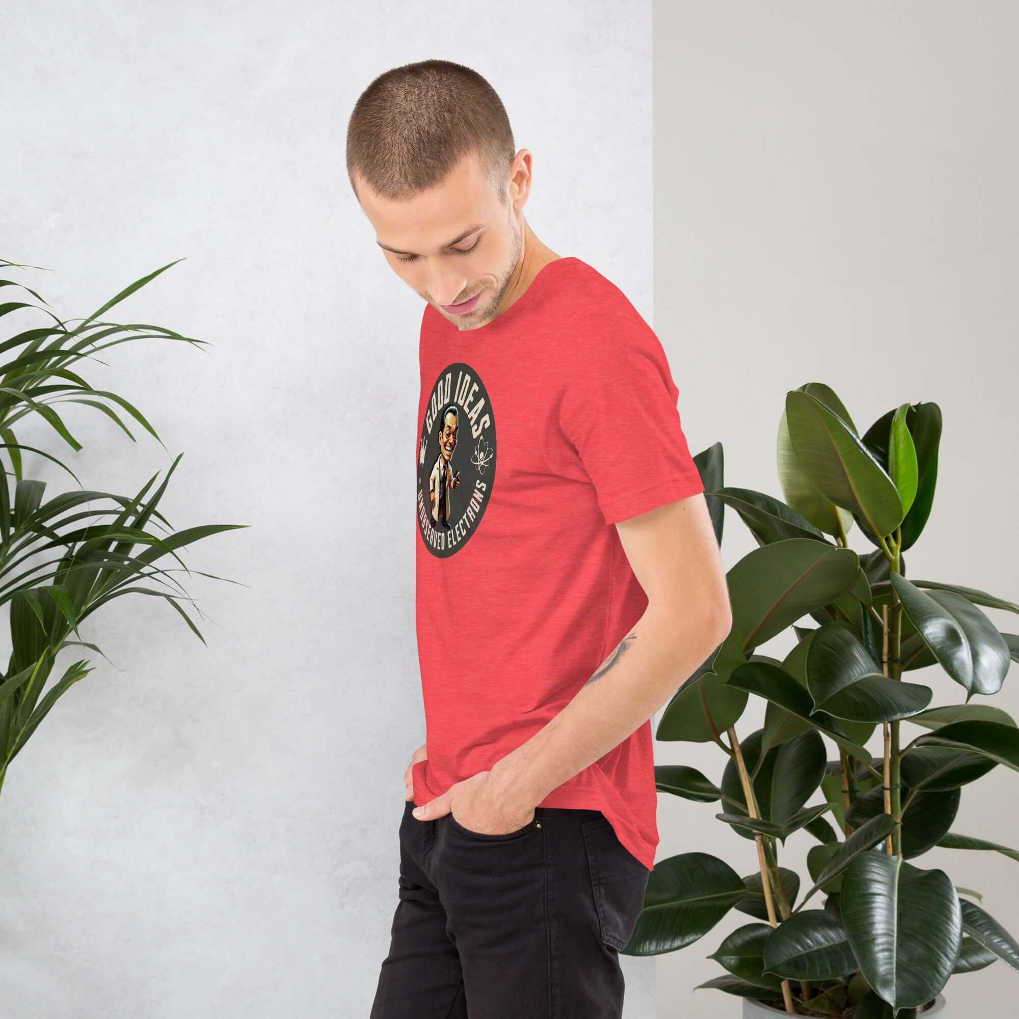 Man wearing red 'Good Ideas Unobserved Electrons' quantum physics humor t-shirt standing near indoor plants.