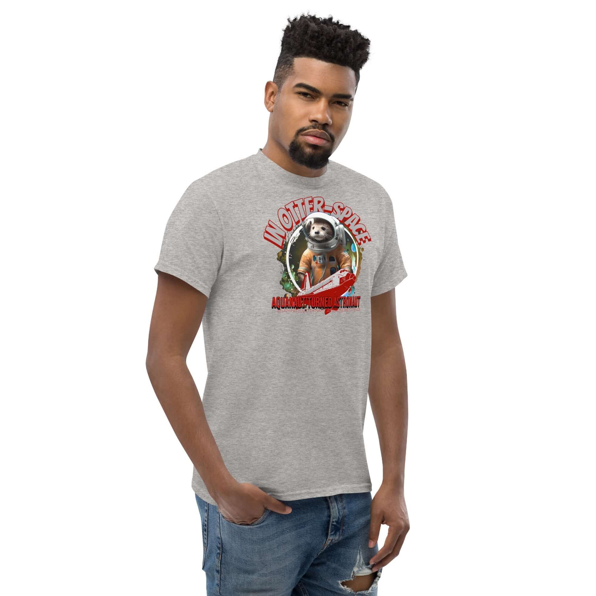 Gray t-shirt featuring otter astronaut design, cosmic background, and text 'In Otter Space: Aquanaut Turned Astronaut'. Modeled by a man.