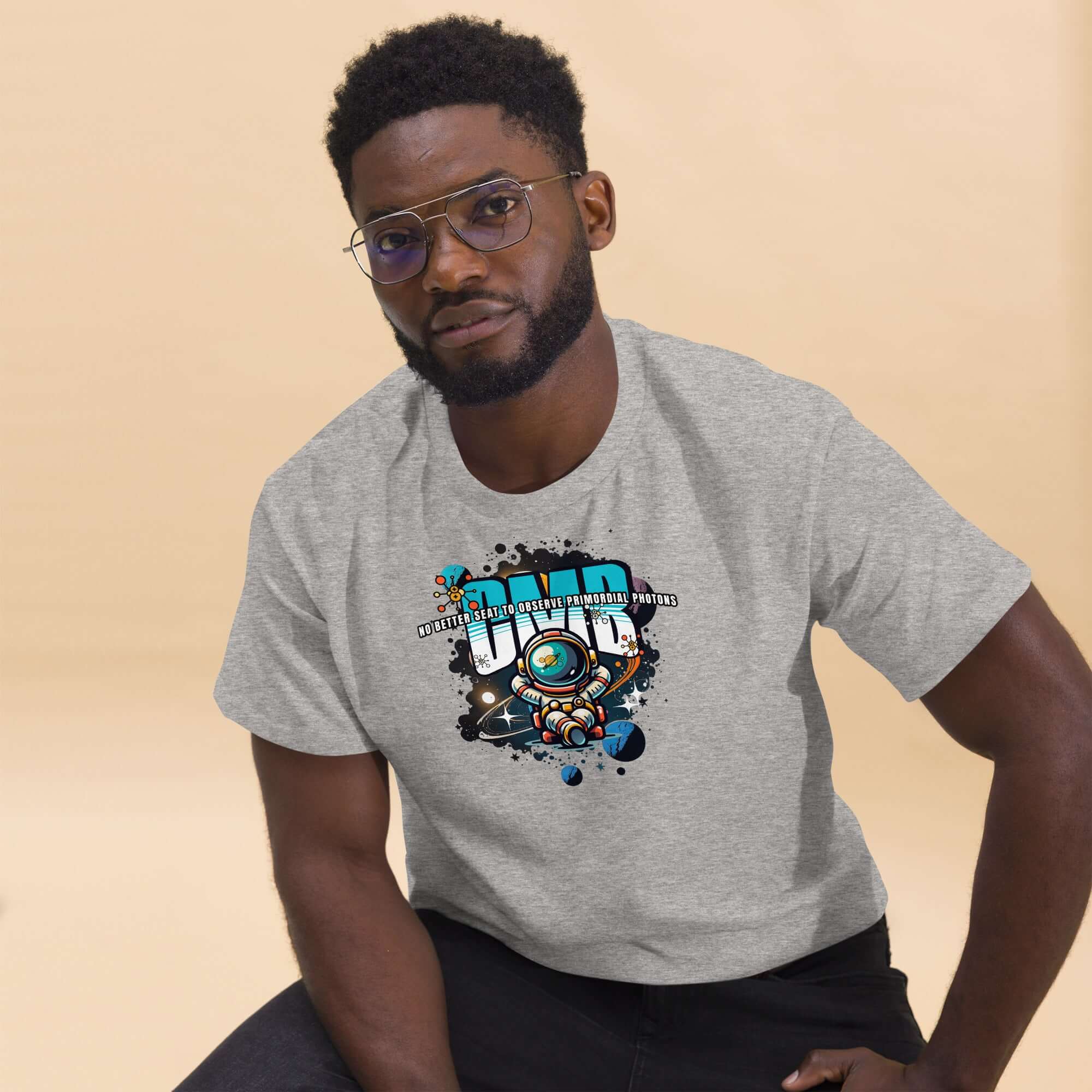 Man wearing Primordial Photons Science T-Shirt with astronaut and planets design, featuring graffiti-style text, in a neutral background.