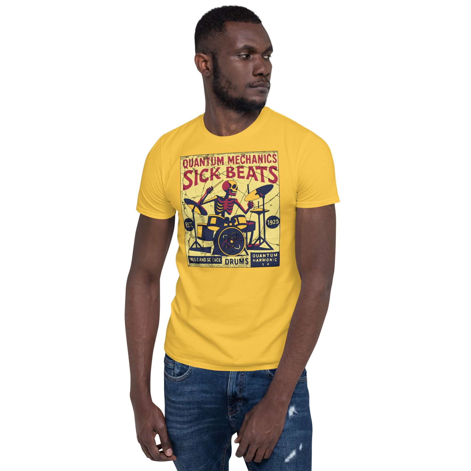 Man wearing a yellow 'Quantum Mechanics Sick Beats' T-shirt featuring a skeleton playing drums, blending physics and music.