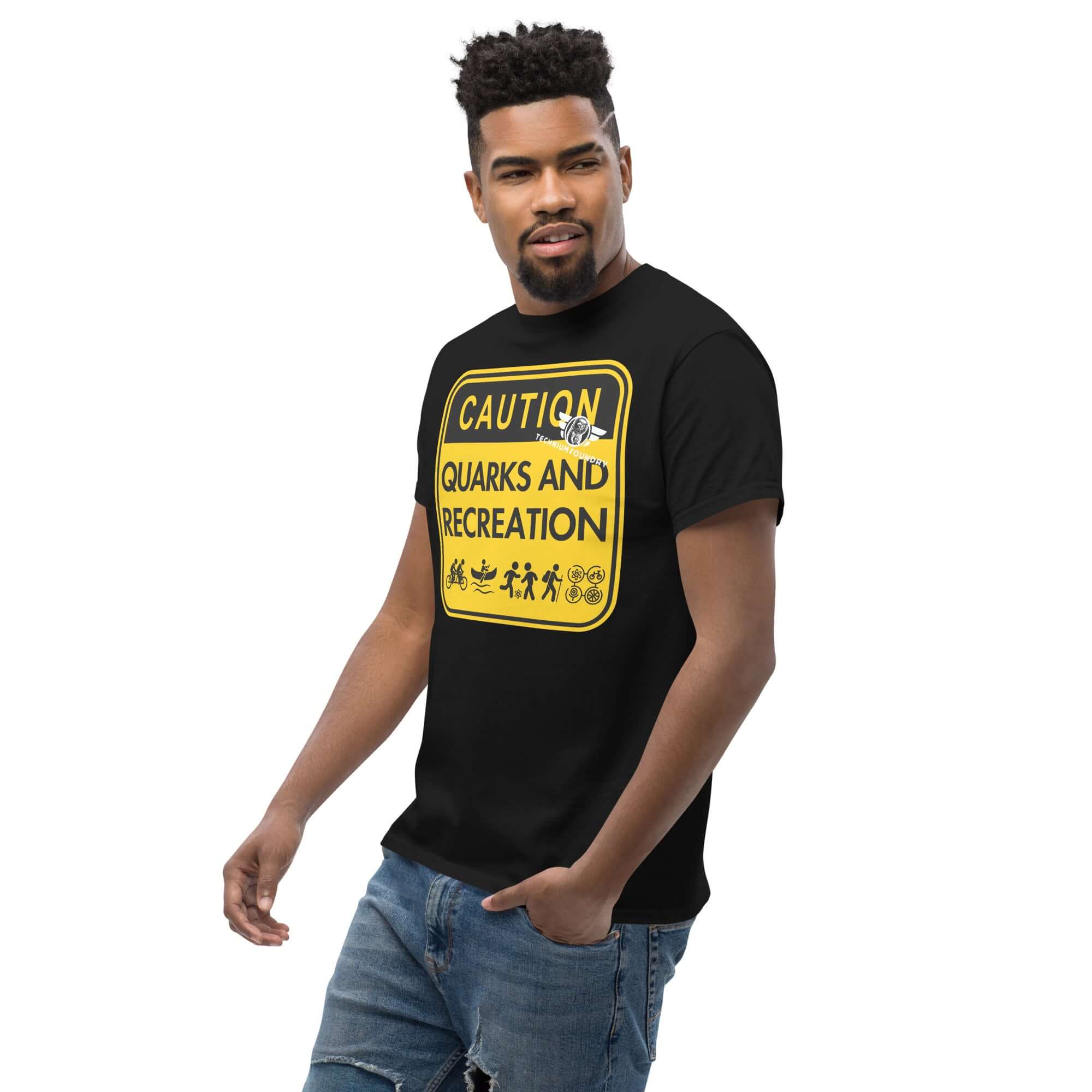 Man wearing a "Quarks and Recreation" t-shirt featuring a humorous particle physics warning sign design in yellow and black.