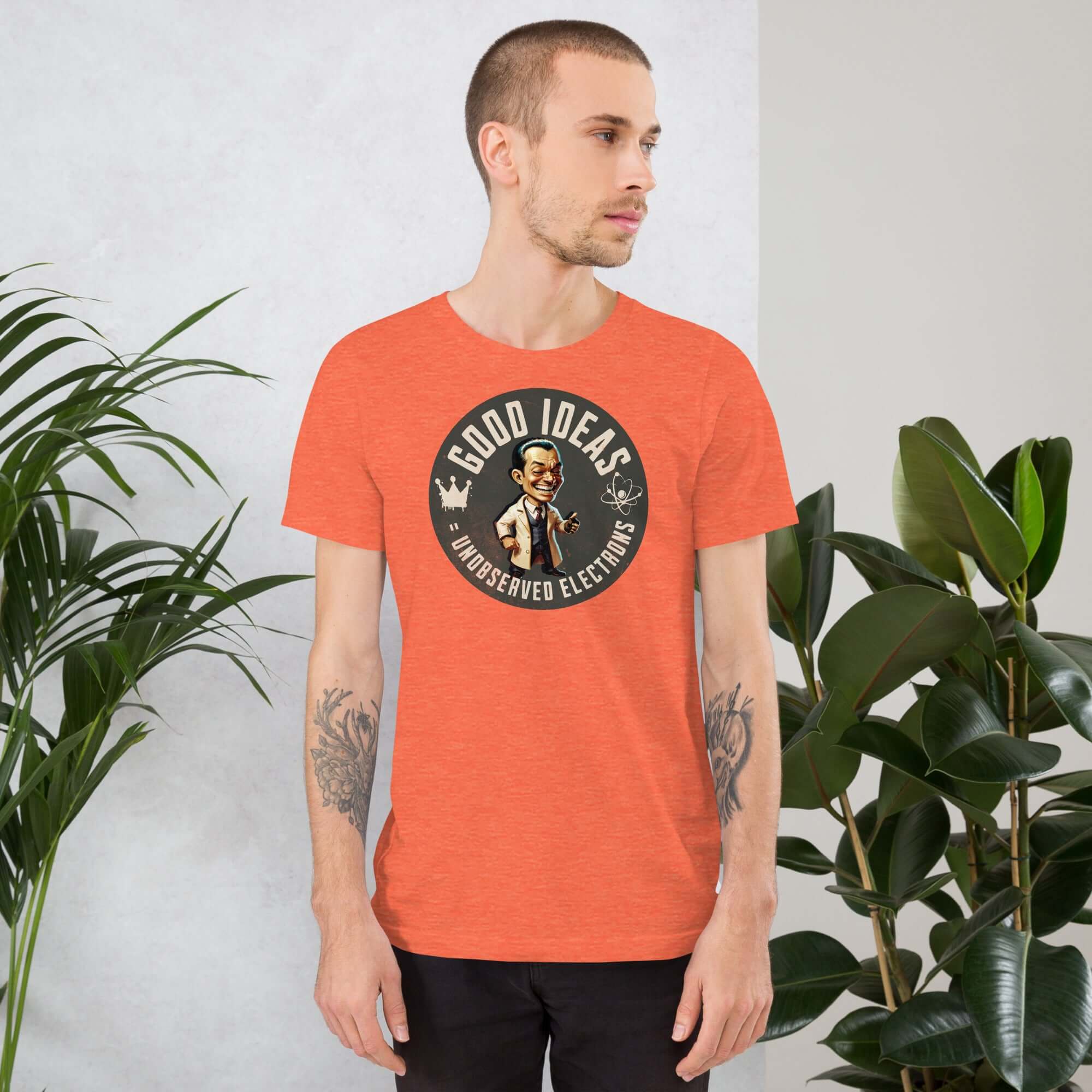 Man wearing a Good Ideas Unobserved Electrons t-shirt with quantum physics humor, standing by indoor plants.