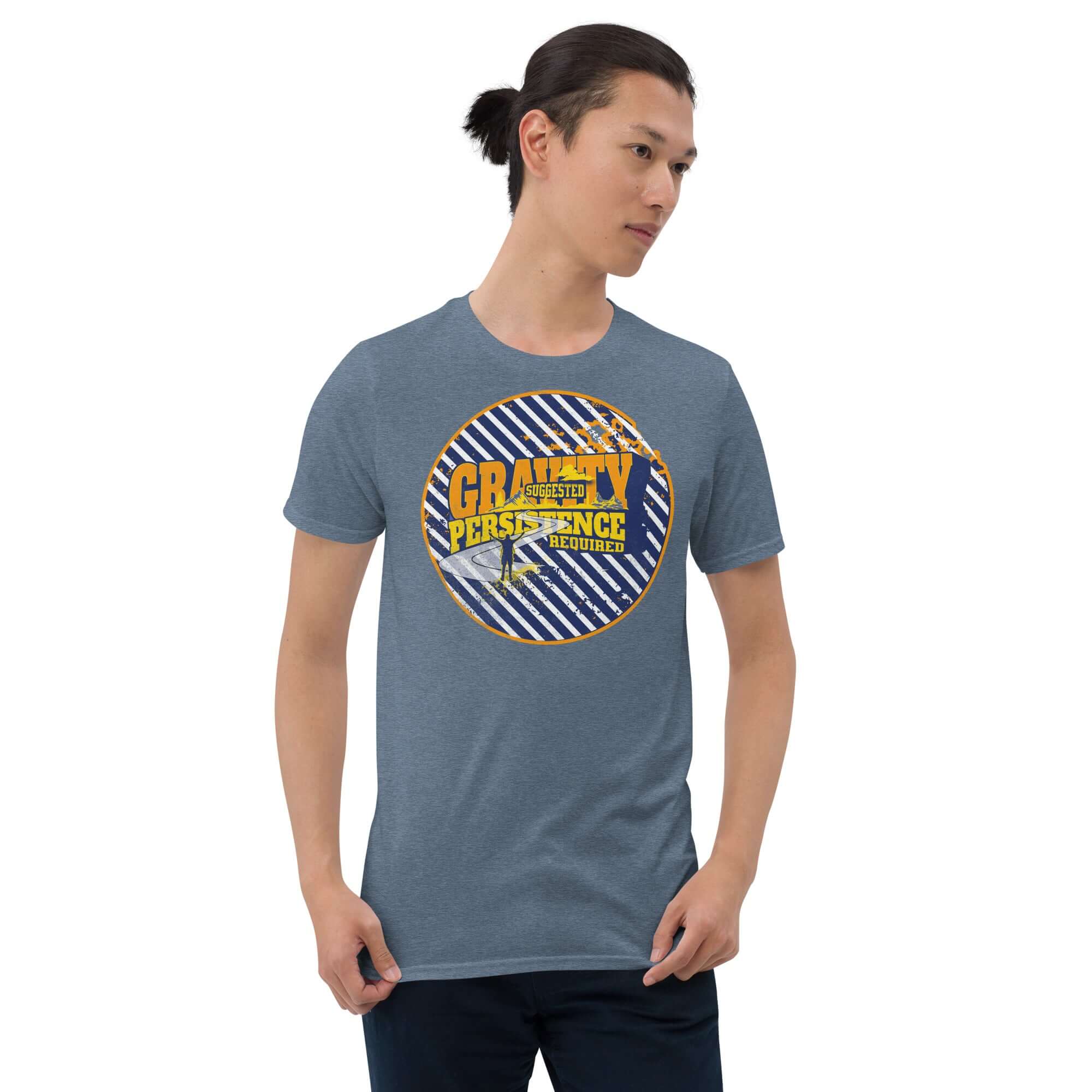 Man wearing 'Gravity: Suggested. Persistence: Required.' navy and white striped t-shirt with golden-yellow typography, standing confidently.