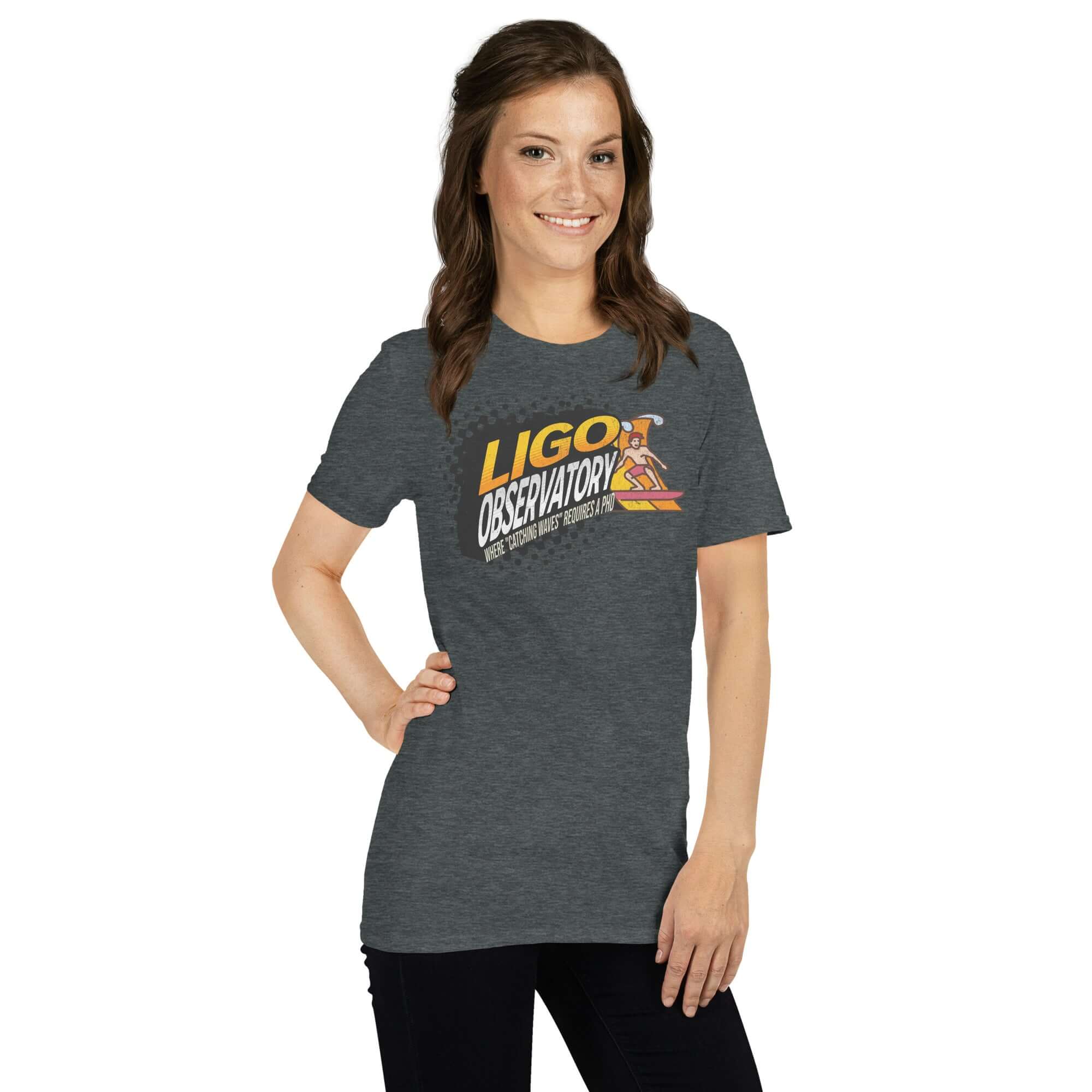 Woman wearing LIGO Observatory T-shirt with "Catching Waves" phrase, featuring yellow-orange gradient lettering on charcoal background.