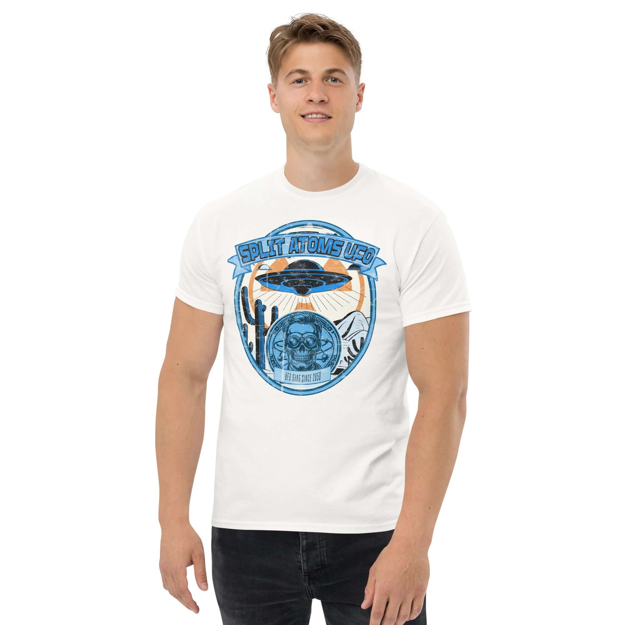 Man wearing white 'Split Atoms UFO' T-shirt featuring retro alien desert design with flying saucer hovering over landscape.
